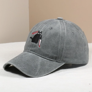 Detail der schwarzen Katzenstickerei und WHAT-Text auf grauer Baseballkappe