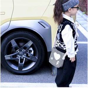 Détail du sac bandoulière enfant à carreaux avec une grande applique cœur blanc en tricot