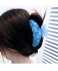 Blue butterfly hair claw with white daisy pattern worn in a natural updo hairstyle
