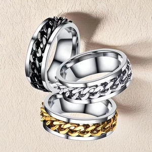 Close-up of three spinning chain rings in silver and gold on a leather surface