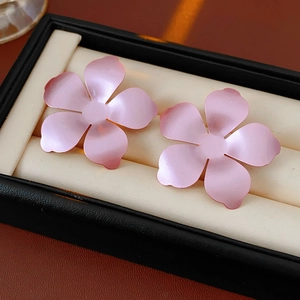 Gros plan détaillé de boucles d'oreilles fleurs roses mates sur un écrin en velours