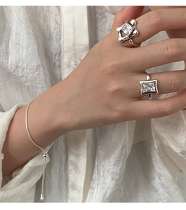 Detailed shot of 925 silver star ring and square diamond ring on a hand