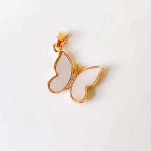 Close-up of 18k gold butterfly pendant featuring white shell wings and inlaid crystals