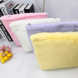 Macro detail of plush candy-colored makeup bags with metal zippers in four pastel shades