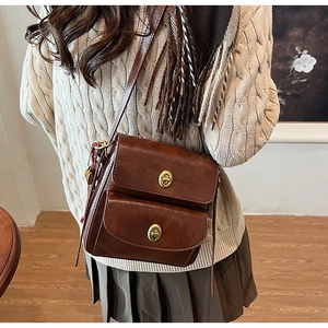 Detail showing the brown faux leather crossbody bag with dual gold twist-lock closures