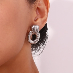 Close-up of textured silver wave hoop earrings worn on a model's ear