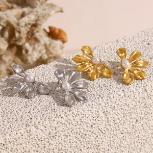 Detailed view of floral stud earrings in gold and silver finish with white pearls