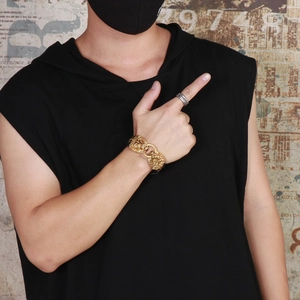 Detail view of golden lion head punk bracelet on male model wrist for street style