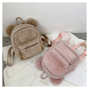 Detail of plush bear-ear backpacks in khaki and pink showing soft fuzzy texture