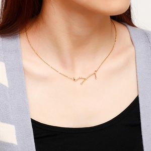 Close-up of a gold-plated zodiac constellation necklace with diamonds on a model neck