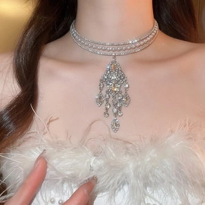 Detailed close-up of a three-layer silver choker with pearls, rhinestones and fringe tassels