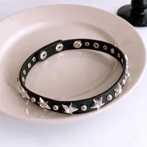 Black leather choker necklace with zircon star rivets and adjustable snaps on a tray