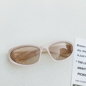 Detail of vintage oval children's sunglasses in beige with brown lenses on artistic wall