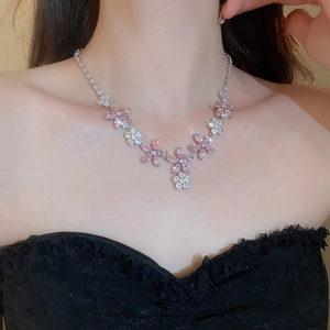Gros plan d'un collier pendentif fleur avec cristaux roses et blancs sur une chaîne argentée