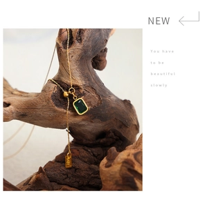 Detail of emerald green zircon square pendant with gold chain and engraved BABY tag
