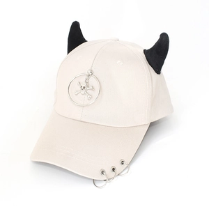 Detail of cream baseball cap featuring black devil horns and silver metal ring charms