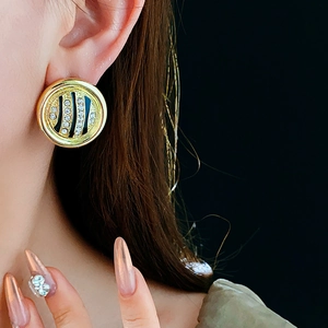 Close-up of gold round earrings with black animal print and rhinestones on model
