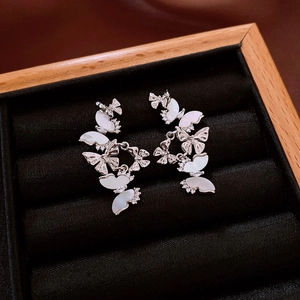 Détail de boucles d'oreilles papillon avec nacre blanche et zircon dans une boîte noire