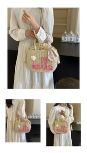 Detail of hand-woven straw bag with pink hello embroidery and floral scarf handle
