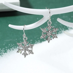 Macro shot of silver snowflake drop earrings with sparkling rhinestones on white antlers