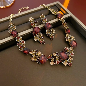 Vintage gold jewelry set with red gemstones and colorful crystals in a dark box