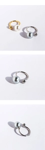Detail of minimalist U-shaped open rings with grey and white pearls in gold and silver finish