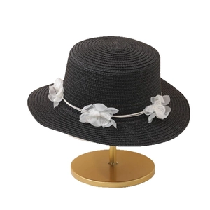 Elegant black flat top straw sun hat with white fabric flower trim on a gold stand