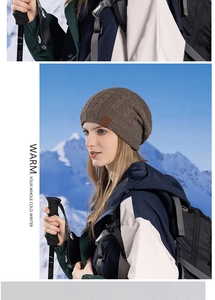 Detail of chunky cable knit texture and leather logo on brown winter beanie outdoors