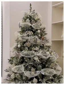 Close-up of a Christmas tree decorated with silver mesh ribbons, ornaments and LED lights