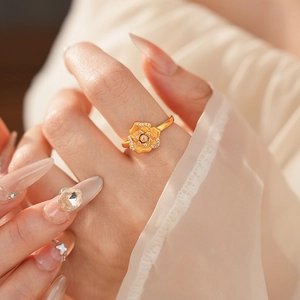 Detailed view of vintage gold floral ring with zircon accents on finger