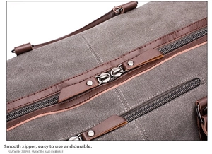 Detail of sturdy metal dual-zipper and brown leather trim on canvas travel bag