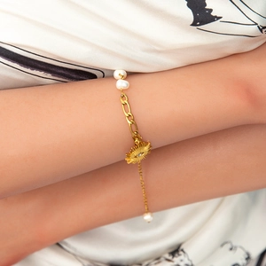 Detail of 18K gold beaded bracelet with freshwater pearls and evil eye sun charm