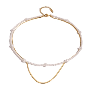 Elegant layered gold snake chain necklace with graduated white pearls on white background