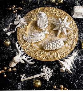 Detailed top view of white and gold embossed Christmas ornaments on a golden tray