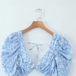 Detail of blue and white porcelain floral blouse with lace V-neck and puff sleeves