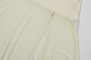 Detail of creamy white knitted dress hem featuring dual symmetrical side slits