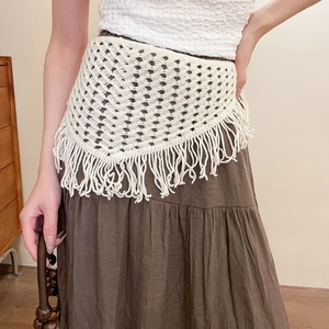 Detail of crochet fringe waist belt featuring hollow geometric knit and cream tassels