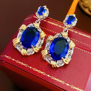 Detailed close-up of vintage oval blue zircon earrings with gold and silver metal settings