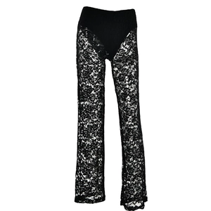 Dettaglio dei pantaloni in pizzo nero a vita alta con motivi floreali trasparenti cuciti