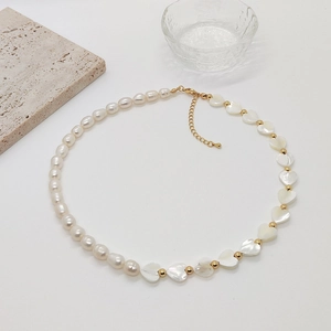 Baroque pearl and heart shell beaded necklace with gold accents on white background