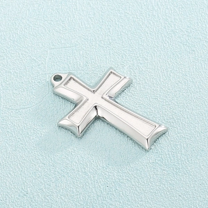 Detailed macro view of polished silver stainless steel cross pendant with top hanging ring