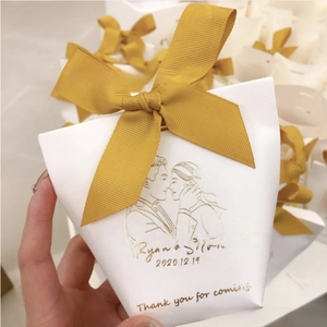 Macro detail of white wedding candy box with golden ribbon and custom couple names