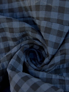 Close-up of deep blue and black gingham fabric texture showing woven threads and soft folds