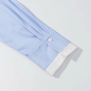 Detailed view of light blue striped shirt cuff with white contrast fabric and single button