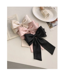 Flat lay of three large French satin bow hair clips in white, pink, and black colors