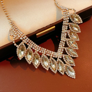 Detail shot of golden crystal teardrop necklace inside a brown premium jewelry gift box