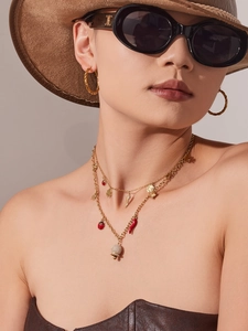 Détail de colliers dorés superposés avec divers pendentifs sur un mannequin