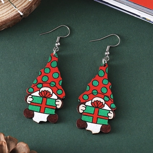 Cute Christmas gnome wooden dangle earrings on a festive green background with pinecones