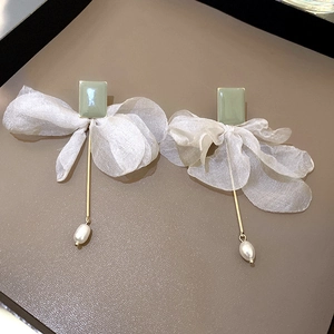 Detail view of long organza bow earrings with green accents and teardrop pearls