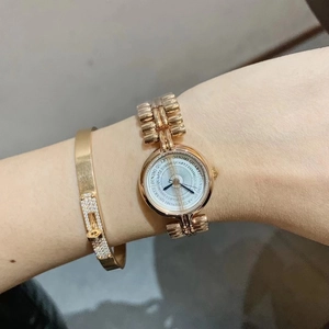 Close-up of a gold quartz bracelet watch with white dial and matching gold bangle